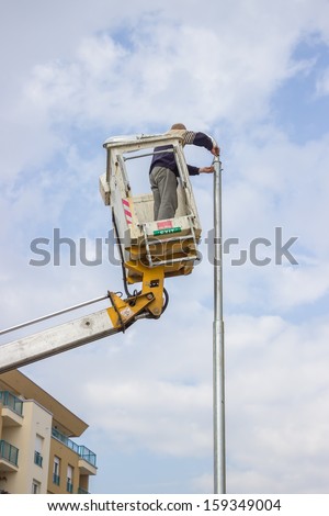 Worker on top of a pole fixing the supply. Maintenance on an electricity pole.