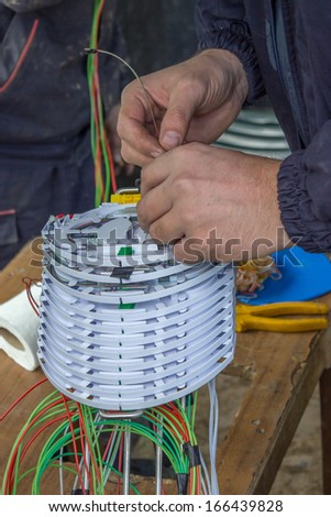 Fibre optic technician sorts optic cables in fiber splice cassettes, splice organiser tray.