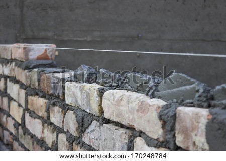 Brick laying, bricklaying spreading a bed joint. Bricklaying foundation walls, spread a mortar bed joint for building brick.
