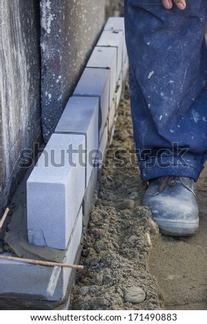 Builder worker installing insulation layer. Brick support systems supplied insulation layer to minimise heat loss, and improve the energy efficiency of a building.