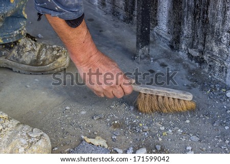 Construction Worker with broom sweeping concrete, preparing to install tile floor