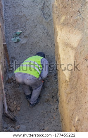 Worker working in trench. No ladder, no hardhat, not working in the trench box. Dangers of trench collapse.