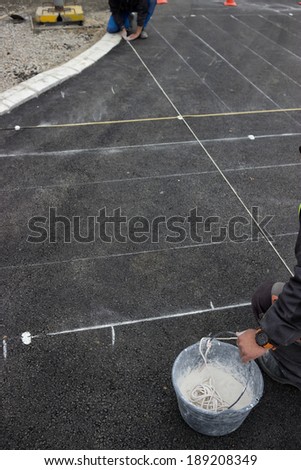 road paint workers with chalk line, string covered in chalk dust. ping a chalk line to mark a  line down and preparing for marking new road lines