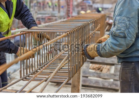 workers hands fixing steel reinforcement bars at construction site
