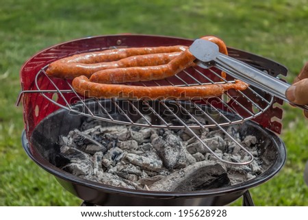 Man Preparing Sausage on Outdoor Grill. Selective focus.