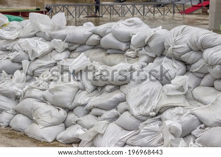 pile of sandbags for flood defense and river in background