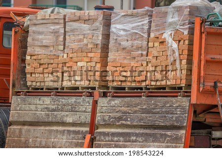 Clay building bricks delivered to the job site in pallets with truck. Selective focus.