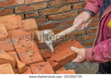 Builder worker cutting a brick. worker need plenty of half bricks to break the bond. Selective focus and motion blur.