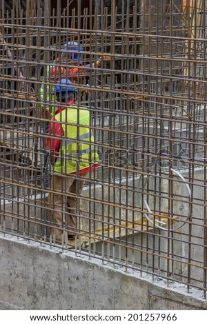 Workers Constructing a rebar cage. Cage will be permanently embedded in poured concrete to create a reinforced concrete structure.