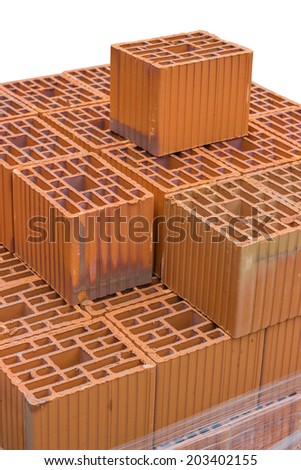 Stacked orange hollow clay block for building construction isolated on white. Selective focus.