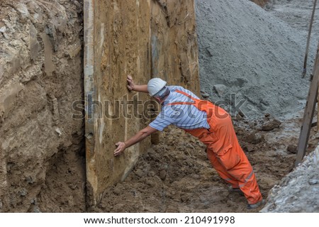 BELGRADE, SERBIA - AUGUST 06: Construction worker in trench working on shoring support. Selective focus. Abstract: Lift safely with backhoes and excavators. At street Vojvode Stepe in August 2014.