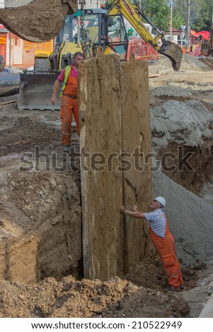 BELGRADE, SERBIA - AUGUST 06: Construction workers in trench Working on shoring support. Selective focus. Abstract: Lift safely with backhoes and excavators. At street Vojvode Stepe in August 2014.
