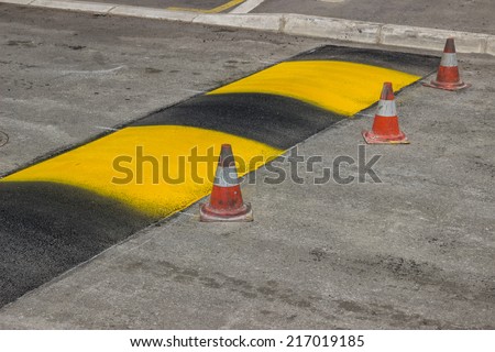 Just painted stripes on a speed bump for slowing traffic near school. Freshly painted speed bump. Selective focus.