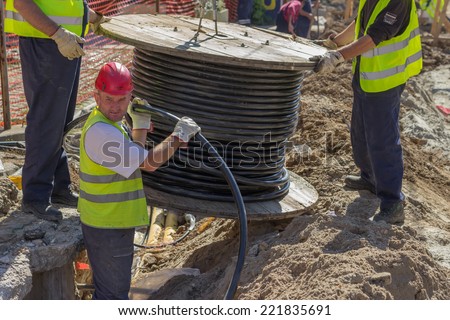BELGRADE, SERBIA - SEPTEMBER 30:  Installing new ground infrastructure in the street. Workers unrolls electrical cable. Selective focus. At street Vojvode Stepe in September 2014.