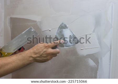 man hand with trowel plastering a wall, skim coating plaster walls