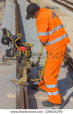 BELGRADE, SERBIA - OCTOBER 29: Tramway track construction worker with rail grinding machine, grinding rail machine. Selective focus. At street Vojvode Stepe in October 2014.