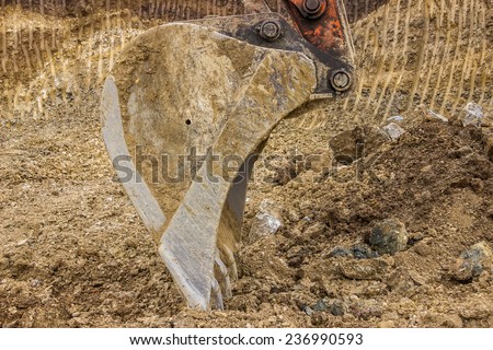 Excavator bucket with yellow and brown dirt texture background. Excavation dirt texture exposed.