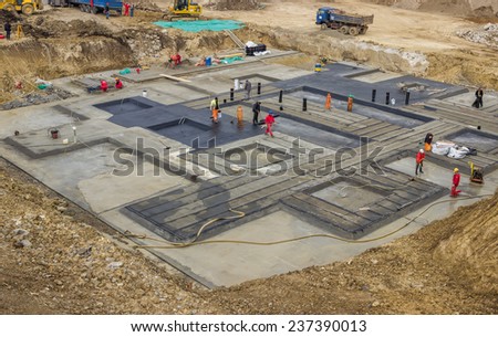 BELGRADE, SERBIA - OCTOBER 30: Foundation insulation workers at ground waterproofing works. Workers melting bitumen felt and water proofing of concrete structure. At construction site in October 2014.
