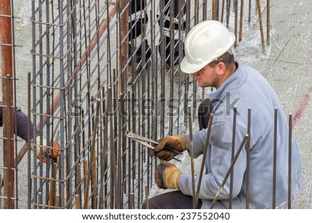 BELGRADE, SERBIA - NOVEMBER 11: Worker working on tying reinforcing steel bars for the construction of a concrete wall. At construction site in November 2014.