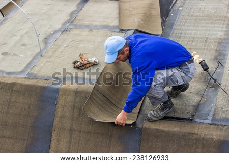 BELGRADE, SERBIA - NOVEMBER 11: Insulation worker and propane blowtorch at floor slab waterproofing works. Worker heating and melting bitumen felt. At construction site in November 2014.