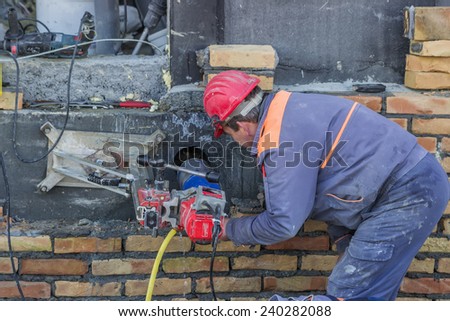 BELGRADE, SERBIA - DECEMBER 24: Worker with core drill, drilling penetration on concrete wall  for pipe. Selective focus. At construction site in December 2014.
