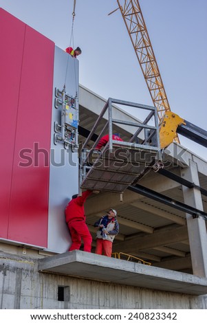 BELGRADE, SERBIA - DECEMBER 27: Builders on aerial access platform connecting sandwich panels for the wall. At construction site in December 2014.