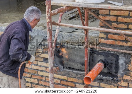BELGRADE, SERBIA - DECEMBER 26: Pipe through the basement wall, outside coated with tar and patched. Basement seal around the waste pipe. At construction site in December 2014.