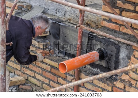 BELGRADE, SERBIA - DECEMBER 26: Pipe through basement wall, outside coated with tar and patched. Basement seal around the waste pipe. Barrier to keep out water. At construction site in December 2014.