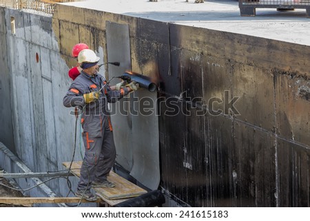 BELGRADE, SERBIA - NOVEMBER 24: Builder worker with propane blow torch melting insulation material on the basement concrete wall. At construction site in November 2014.