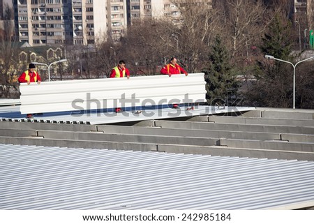 BELGRADE, SERBIA - DECEMBER 13: Roof sheet metal workers installing roof panels. Fastening metal roofing. Selective focus. At construction site in December 2014.