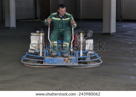 BELGRADE, SERBIA - JANUARY 13: Ride on machine with trowels and worker, flat concrete floor. Double power trowel finishing concrete floor. At construction site in January 2015.