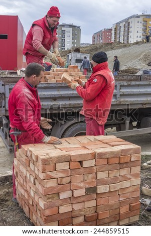 BELGRADE, SERBIA - JANUARY 17: Workers unload trucks with clay bricks, builder workers teamwork. At  construction site in January 2015.