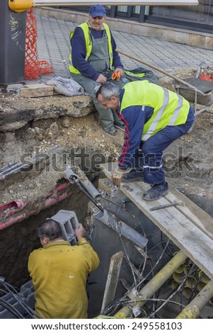 BELGRADE, SERBIA - JANUARY 14: Looking down into hole with electric cables and worker. At construction site in January 2015.