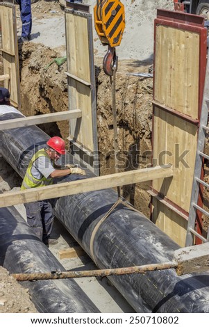 BELGRADE, SERBIA - AUGUST 23: Installing the district heating pipe systems. Laying huge pipe in a trench. At construction site in August 2014.