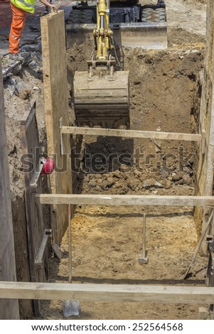 excavator digging trench for the ground piping at construction site