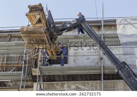 BELGRADE, SERBIA - MARCH 17: Scaffolding workers unloading wood structure on scaffolding from forklift. At construction site in March 2015.