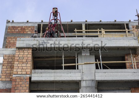 BELGRADE, SERBIA - MARCH 19: Cosntruction workers using electric construction scaffolding lifting winch hoist. At construction site in March 2015.