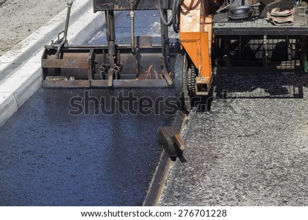 Installation of hard and cast molten asphalt. Working on a tram track construction project. Selective focus and shallow dof.
