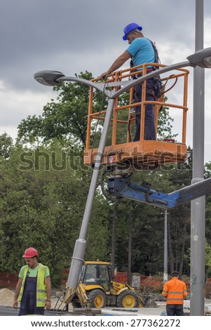 BELGRADE, SERBIA - MAY 10: Close of workers during installation of metal pole with street lamp, street light. Selective focus and shallow dof. Working on a street reconstruction project in May 2015.