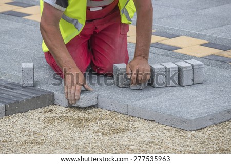 Mason hands laying paver bricks, paver making sidewalk. Selective focus and shallow dof.