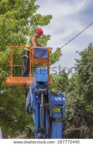 BELGRADE, SERBIA - JUNE 08: Electrical worker in lift bucket during repair the power line. Selective focus and shallow dof. Utility worker replacing cables in June 2015.
