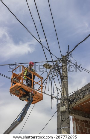 BELGRADE, SERBIA - JUNE 08: Utility worker fixes the power line, connecting cables from lift bucket in June 2015.