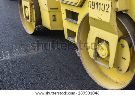 Close of road roller compacting asphalt. Compactor roller during street paving works. Selective focus and shallow dof.