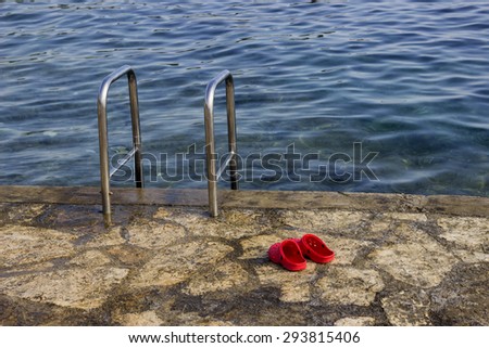 Metal stairs to sea water. Stairs to the sea and red slippers. Selective focus and shallow dof.
