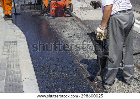Workers laying stone mastic asphalt during street repairing works. Selective focus and shallow dof.