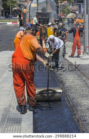 BEOGRAD, SERBIA - JULY 16, 2015: Crew laying asphalt mastic surface, during street repairing works. Selective focus and shallow dof.