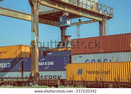 BELGRADE, SERBIA - OCTOBER 28, 2015: Portal crane lifting container from train trailer. Containers and container handling, rail mounted crane. Made with vintage style.