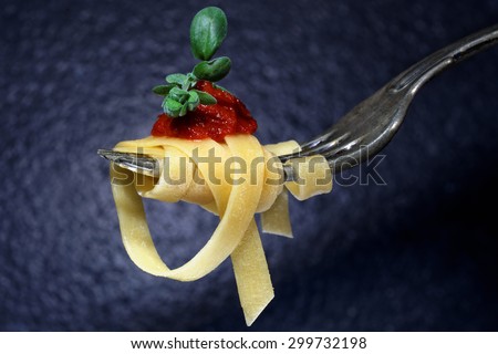 Spaghetti on a fork is served with tomato sauce and basi