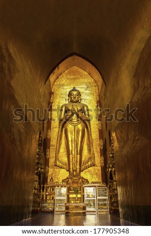 BAGAN, MYANMAR - NOVEMBER 30: Standing Buddha Kassapa at south facing part of the Ananda temple adorned by believers by sticking golden leaves on statue on NOVEMBER 30, 2013 in Bagan, Myanmar.