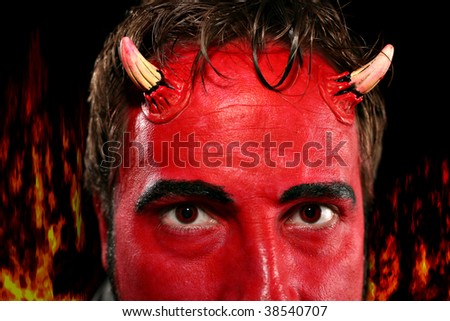 Closeup of the horns and eyes of a devil character, fire flames in background.